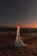 Fototapeta na wymiar bride on the beach an a beautiful sunset as background