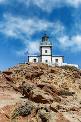 Fototapeta na wymiar The old lighthouse on the rocky sea coast. Blue sky with clouds.
