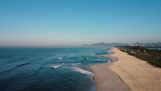 Aerial view of Reserva beach, Marapendi lagoon and car traffic on Lucio Costa avenue. Barra da Tijuca and Recreio, in Rio de Janeiro, Brazil. Sunrise. Sunny day. Drone take. Praia da Reserva.
