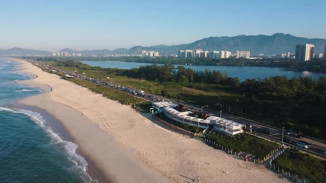 Aerial view of Reserva beach, Marapendi lagoon and car traffic on Lucio Costa avenue. Barra da Tijuca and Recreio, in Rio de Janeiro, Brazil. Sunrise. Sunny day. Drone take. Praia da Reserva.