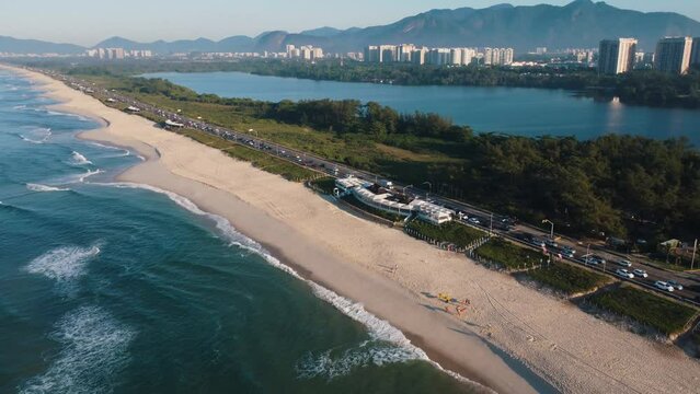 Aerial view of Reserva beach, Marapendi lagoon and car traffic on Lucio Costa avenue. Barra da Tijuca and Recreio, in Rio de Janeiro, Brazil. Sunrise. Sunny day. Drone take. Praia da Reserva.