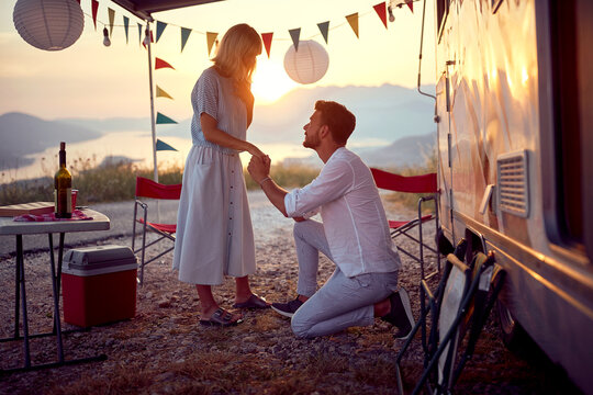 A young man is proposing his girlfriend during a vacation in the camp in the nature. Relationship, love, camping, nature