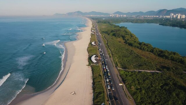 Aerial view of Reserva beach, Marapendi lagoon and car traffic on Lucio Costa avenue. Barra da Tijuca and Recreio, in Rio de Janeiro, Brazil. Sunrise. Sunny day. Drone take. Praia da Reserva.
