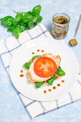 Sandwich with chicken, mozzarella, tomato, pesto and basil on toasted ciabatta, vertical, top view