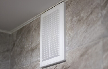 Ventilation grille in white on gray marble tiles