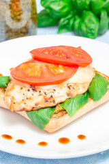 Sandwich with chicken, mozzarella, tomato, pesto and basil on toasted ciabatta, vertical