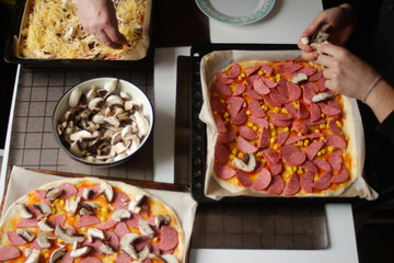 Defocus ingredients for pizza on dough. Man cooking. Red tomato sauce, sausages, sweet corn, mushrooms, cheese. Homemade pizza. Base of Margarita. Home culinary, fast food.  Out of focus