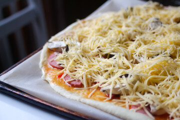 Defocus closeup round whole pizza with freshly grated mozzarella cheese. Defocus blurred ingredients for pizza on dough. Copy space. Italian cuisine background. Backdrop. Fresh Margarita Out of focus