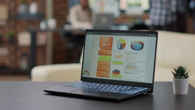 Laptop screen with financial charts and graphs on office desk, computer display showing data statistics and analysis diagram. Modern device with sales reports and research. Close up.