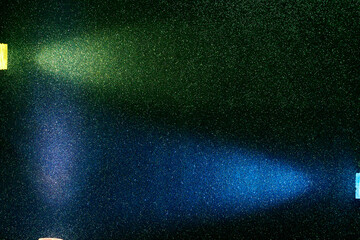 On a dark green gradient background in fine grain, rays of violet green and blue light