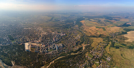 Obraz premium Aerial view from airplane window at high altitude of earth covered with white thin layer of misty haze and distant clouds at sunset