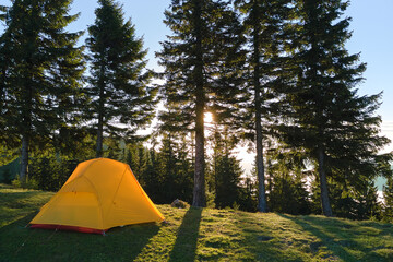 Tourist camping tent on mountain campsite at bright sunny evening. Active tourism and hiking concept