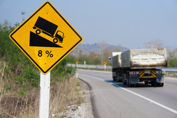 Yellow traffic sign  to warn  truck driver to drive carefully down to hill on slope a steep 8 percent(8%) downhill gradient beside the road.  Concept : Traffic Road Sign and symbol.