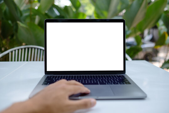 Mockup image of a man using laptop computer with blank white desktop screen in the outdoors