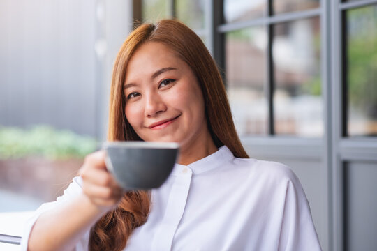 Portrait image of a beautiful young asian woman holding, giving and drinking hot coffee