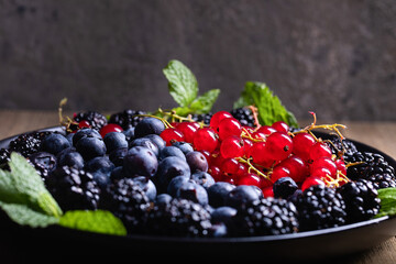 berries  currant blackberry blueberry on a plate on a wooden table