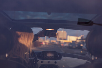 Eine Frau fährt Auto in der Stadt bei Sonnenuntergang