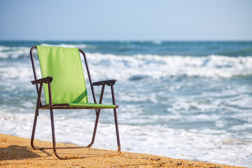 one green folding chair on the sea beach