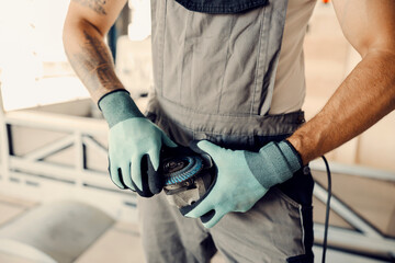 Close up of mechanic adjusting grinder for work at workshop. - obrazy, fototapety, plakaty