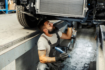 An auto-mechanic repairing bus at workshop.