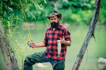 Portrait of fisher man using rod flyfishing in mountain river. A fly fisherman fishing for wild trout on the river in the forest. Spring holiday.