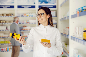 A friendly pharmacist holding pills and medicines and recommending illness prevention.