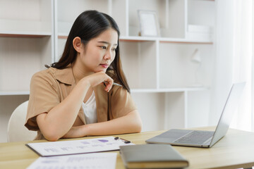 Online lifestyle concept A female worker paying attention on reading some data of her work on the laptop’s screen