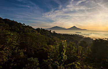 Obraz premium Beautiful Scene of Merapi Merbabu Mountain at Sunrise time from Punthuk Setumbu. In front of the mountain there is silhouette of Borobudur temple. 