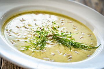 Cream zucchini soup with sunflower seeds and fresh dill on wooden table