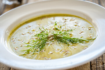 Cream zucchini soup with sunflower seeds and fresh dill on wooden table