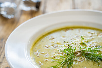 Cream zucchini soup with sunflower seeds and fresh dill on wooden table