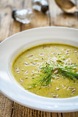 Cream zucchini soup with sunflower seeds and fresh dill on wooden table