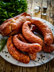Smoked sausages and ham on wooden table