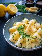 White boiled asparagus in hollandaise sauce with potato puree served on  wooden black table	