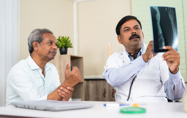 doctor explaining by seeing x-ray report to senior elderly patient at hospital - concep tof medical treatment, assistance and Healthcare