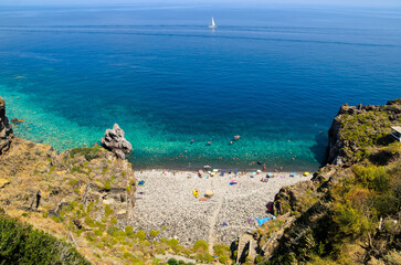 Aerial view of the crystal clear sea water at Spiaggia dello Scario beach in Malfa, Salina, Aeolian Islands. People enjoy the sun and sand on a clear summer day. Beautiful holiday destination.
