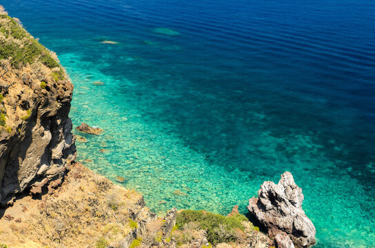 Aerial view of the crystal clear sea water at Spiaggia dello Scario beach in Malfa, Salina, Aeolian Islands. People enjoy the sun and sand on a clear summer day. Beautiful holiday destination.
