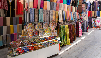 Dubai, UAE. View of the old Bur Dubai textile souk market in Creek district. Colorful stores with textiles goods, souvenirs and accessories. Touristic destination - obrazy, fototapety, plakaty