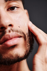 Close-up of handsome young guy applying face cream on his face for protection