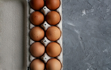 Dotted brown eggs lie in a paper bag on a gray concrete table