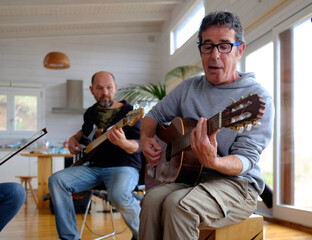 middle-aged musicians playing guitar during a band rehearsal.
