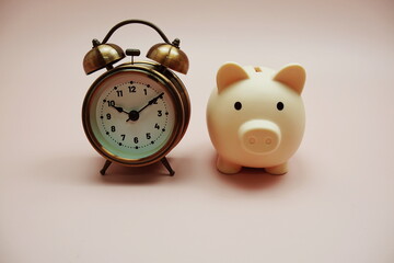 Piggy bank and alarm clock with space copy on pink background
