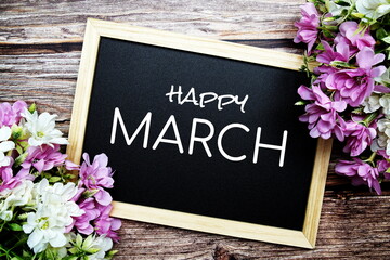 Happy March typography text written on wooden blackboard with flower bouquet decorate on wooden background