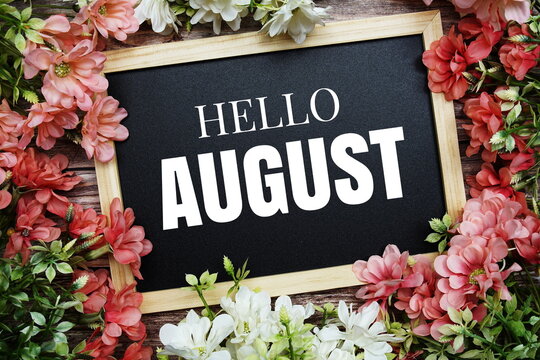 Hello August typography text written on wooden blackboard with flower bouquet decorate on wooden background