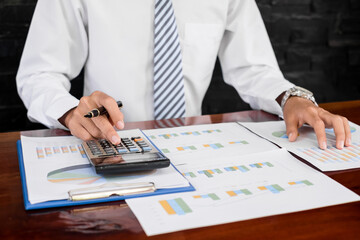 Fototapeta premium The businessman hand sits at their desks and calculates financial graphs showing the results of their investments planning the process of successful business growth