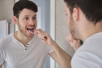 Close up of young latin man removing orthodontic silicone trainer in front of the mirror. Mobile...