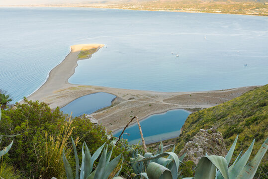 Turquoise calm sea water and sand dunes of Riserva Naturale Orientata Laghetti di Marinello, seen from the Sanctuary of the Black Madonna of Tindari.
