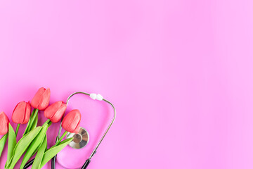Happy nurse's day. Health day. Stethoscope, red tulips, on pink background. Greeting background. National doctor's day. Top view, Copy space on right. Thank you, doctors and nurses. Selective focus