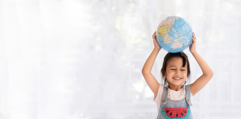 Banner of happy aasian little girl is raising the globe model with love and concept of preserve, save and protect the earth from environment problem and global warming, kid education at home.