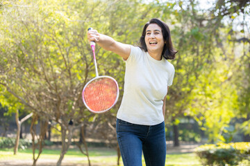 Mature indian woman playing badminton in the park. urban asian sporty female having fun outdoor sports and game activity concept. - obrazy, fototapety, plakaty